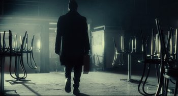 A man walking in the dark holding a bag of luggage