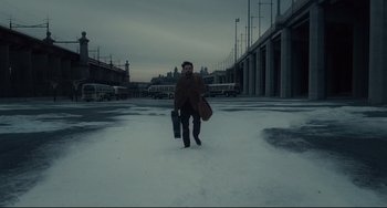Movie still from “Inside Llewyn Davis” (2013), directed by Ethan Coen – A man walking across a snow covered street holding a suitcase; Wide shot, High angle