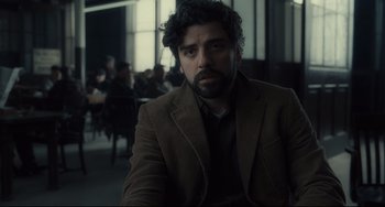 Movie still from “Inside Llewyn Davis” (2013), directed by Ethan Coen – A man in a brown jacket sitting in front of a group of people; Close Up shot, Over the shoulder angle