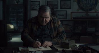 Movie still from “Inside Llewyn Davis” (2013), directed by Ethan Coen – An older man writing on a piece of paper; Medium shot, High angle