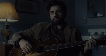 Movie still from “Inside Llewyn Davis” (2013), directed by Ethan Coen – A man holding a guitar in a dark room; Close Up shot, Over the shoulder angle
