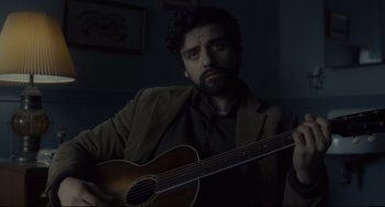 Movie still from “Inside Llewyn Davis” (2013), directed by Ethan Coen – A man holding a guitar in a dark room; Close Up shot, Over the shoulder angle