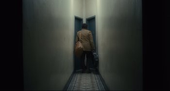 Movie still from “Inside Llewyn Davis” (2013), directed by Ethan Coen – A man with a bag is walking down a hallway; Wide shot, Low angle