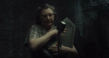 Movie still from “Inside Llewyn Davis” (2013), directed by Ethan Coen – An older woman holding an accordion and a microphone; Medium shot, Low angle