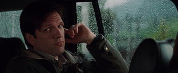 Movie still from “Insomnia” (2002), directed by Christopher Nolan – A man sitting in a car looking out the window; Close Up shot, Low angle