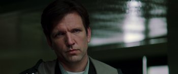 Movie still from “Insomnia” (2002), directed by Christopher Nolan – A person wearing a jacket looking at the camera; Close Up shot, Over the shoulder angle