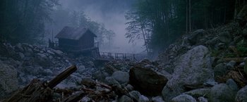 Movie still from “Insomnia” (2002), directed by Christopher Nolan – A wooden bridge over a body of water near a forest; Extreme Wide shot, High angle