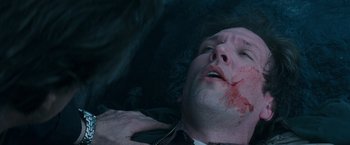 Movie still from “Insomnia” (2002), directed by Christopher Nolan – A man with blood on his face is laying on the ground; Close Up shot, Overhead angle