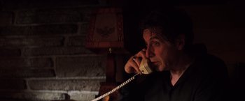 Movie still from “Insomnia” (2002), directed by Christopher Nolan – A man talking on a phone while sitting in a room; Close Up shot, Low angle