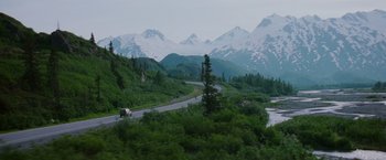 Movie still from “Insomnia” (2002), directed by Christopher Nolan – A truck driving down a road in the middle of a forest; Extreme Wide shot, High angle