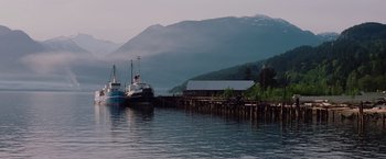 Movie still from “Insomnia” (2002), directed by Christopher Nolan – Two boats are docked at a pier in a body of water; Extreme Wide shot, Low angle