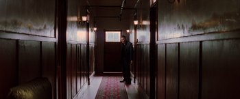 Movie still from “Insomnia” (2002), directed by Christopher Nolan – A man standing in a hallway with a door open; Wide shot, Low angle