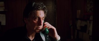 Movie still from “Insomnia” (2002), directed by Christopher Nolan – A man talking on a phone while sitting down; Close Up shot, Low angle