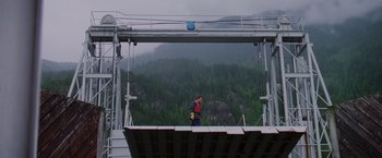 Movie still from “Insomnia” (2002), directed by Christopher Nolan – A man standing on a platform in front of trees; Extreme Wide shot, Low angle