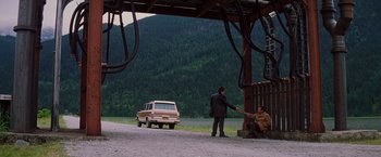 Movie still from “Insomnia” (2002), directed by Christopher Nolan – A man standing next to a car on the side of a road; Wide shot, Over the shoulder angle