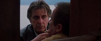 Movie still from “Insomnia” (2002), directed by Christopher Nolan – A man looking at another man's reflection in a mirror; Close Up shot, Over the shoulder angle
