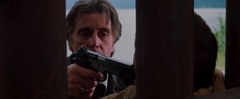Movie still from “Insomnia” (2002), directed by Christopher Nolan – A man holding a gun in his hand and aiming at something; Close Up shot, Over the shoulder angle