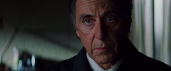 Movie still from “Insomnia” (2002), directed by Christopher Nolan – An older man in a suit and tie looking at the camera; Close Up shot, Low angle