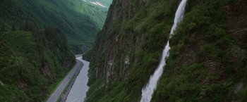 Movie still from “Insomnia” (2002), directed by Christopher Nolan – A view of a waterfall on a mountain side; Extreme Wide shot, High angle