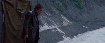 Movie still from “Insomnia” (2002), directed by Christopher Nolan – A man standing on top of a cliff looking at the sky; Medium shot, Low angle