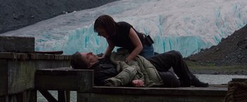 Movie still from “Insomnia” (2002), directed by Christopher Nolan – A man and a woman laying on the ground near a body of water; Wide shot, High angle