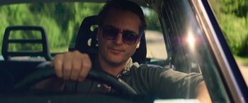 Movie still from “Irrational Man” (2015), directed by Woody Allen – A person driving a car wearing sunglasses; Close Up shot, Low angle