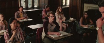 Movie still from “Irrational Man” (2015), directed by Woody Allen – A group of people sitting at a table in a room; Medium shot, Over the shoulder angle
