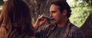 Movie still from “Irrational Man” (2015), directed by Woody Allen – A man holding a cell phone up to his mouth; Close Up shot, Over the shoulder angle