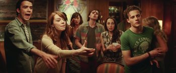 Movie still from “Irrational Man” (2015), directed by Woody Allen – A group of people standing in a living room; Medium shot, Over the shoulder angle