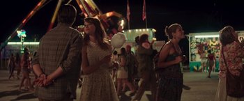 Movie still from “Irrational Man” (2015), directed by Woody Allen – A woman in a white dress holding a cotton candy; Medium shot, Over the shoulder angle