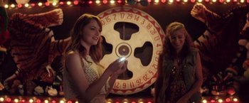 Movie still from “Irrational Man” (2015), directed by Woody Allen – Two women standing in front of a wheel of fortune; Medium shot, Over the shoulder angle