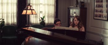 Movie still from “Irrational Man” (2015), directed by Woody Allen – Two women are sitting at a piano in a living room; Medium shot, Over the shoulder angle