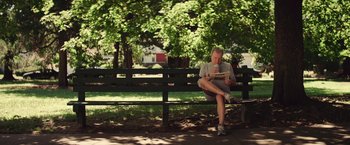 Movie still from “Irrational Man” (2015), directed by Woody Allen – A man sitting on top of a wooden park bench; Wide shot, Low angle