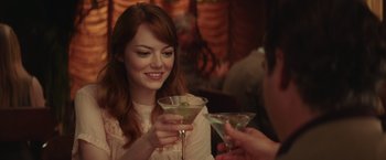 Movie still from “Irrational Man” (2015), directed by Woody Allen – A woman holding a martini glass and looking at a man; Close Up shot, Over the shoulder angle