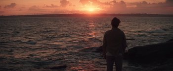 Movie still from “Irrational Man” (2015), directed by Woody Allen – A man standing in the water watching the sun go down; Extreme Wide shot, Over the shoulder angle