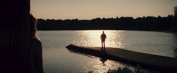 Movie still from “Irrational Man” (2015), directed by Woody Allen – A man standing on a pier in the middle of a lake at sunset; Extreme Wide shot, High angle