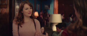 Movie still from “Irrational Man” (2015), directed by Woody Allen – A woman standing in front of a group of people; Medium shot, Over the shoulder angle