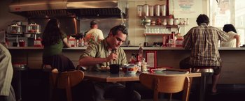 Movie still from “Irrational Man” (2015), directed by Woody Allen – A man sitting at a table with a bowl of food in front of him; Medium shot, Over the shoulder angle