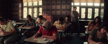 Movie still from “Irrational Man” (2015), directed by Woody Allen – A group of people sitting at a desk writing; Wide shot, High angle