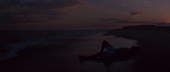 Movie still from “Jaws” (1975), directed by Steven Spielberg – A person laying on the beach at night; Extreme Wide shot, High angle