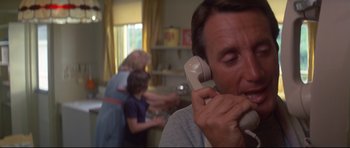 Movie still from “Jaws” (1975), directed by Steven Spielberg – A man talking on a phone in a room with other people; Close Up shot, Low angle