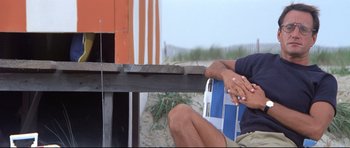 Movie still from “Jaws” (1975), directed by Steven Spielberg – A man sitting on a chair next to a wooden fence; Medium shot, High angle