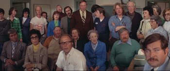 Movie still from “Jaws” (1975), directed by Steven Spielberg – A group of people that are sitting in a room together; Medium shot, High angle