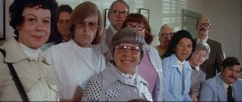 Movie still from “Jaws” (1975), directed by Steven Spielberg – A group of people standing in front of each other wearing glasses; Medium shot, Low angle