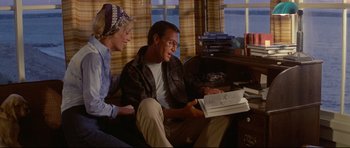 Movie still from “Jaws” (1975), directed by Steven Spielberg – A man and a woman sitting on a couch looking at a book; Medium shot, High angle