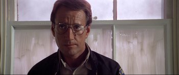 Movie still from “Jaws” (1975), directed by Steven Spielberg – A person wearing glasses and a police uniform; Close Up shot, Low angle