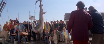 Movie still from “Jaws” (1975), directed by Steven Spielberg – A group of people standing next to a large shark; Wide shot, Low angle