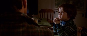 Movie still from “Jaws” (1975), directed by Steven Spielberg – A young boy sitting at a table with his hands clasped together; Medium shot, High angle