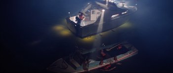 Movie still from “Jaws” (1975), directed by Steven Spielberg – A man standing on the side of a boat in the water; Extreme Wide shot, High angle