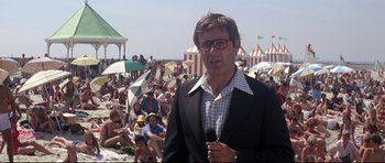 Movie still from “Jaws” (1975), directed by Steven Spielberg – A man in a black suit is holding a microphone; Medium shot, Low angle